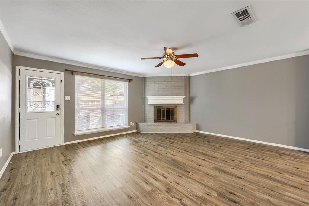 Living room with a wood-burning brick fireplace and wood look flooring at 22 E Townhouse Ln #31, Grand Prairie